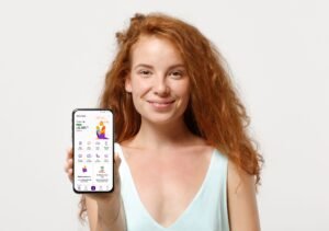 Young smiling redhead woman girl in casual light clothes posing isolated on white background, studio portrait. People lifestyle concept. Mock up copy space. Hold mobile phone with blank empty screen